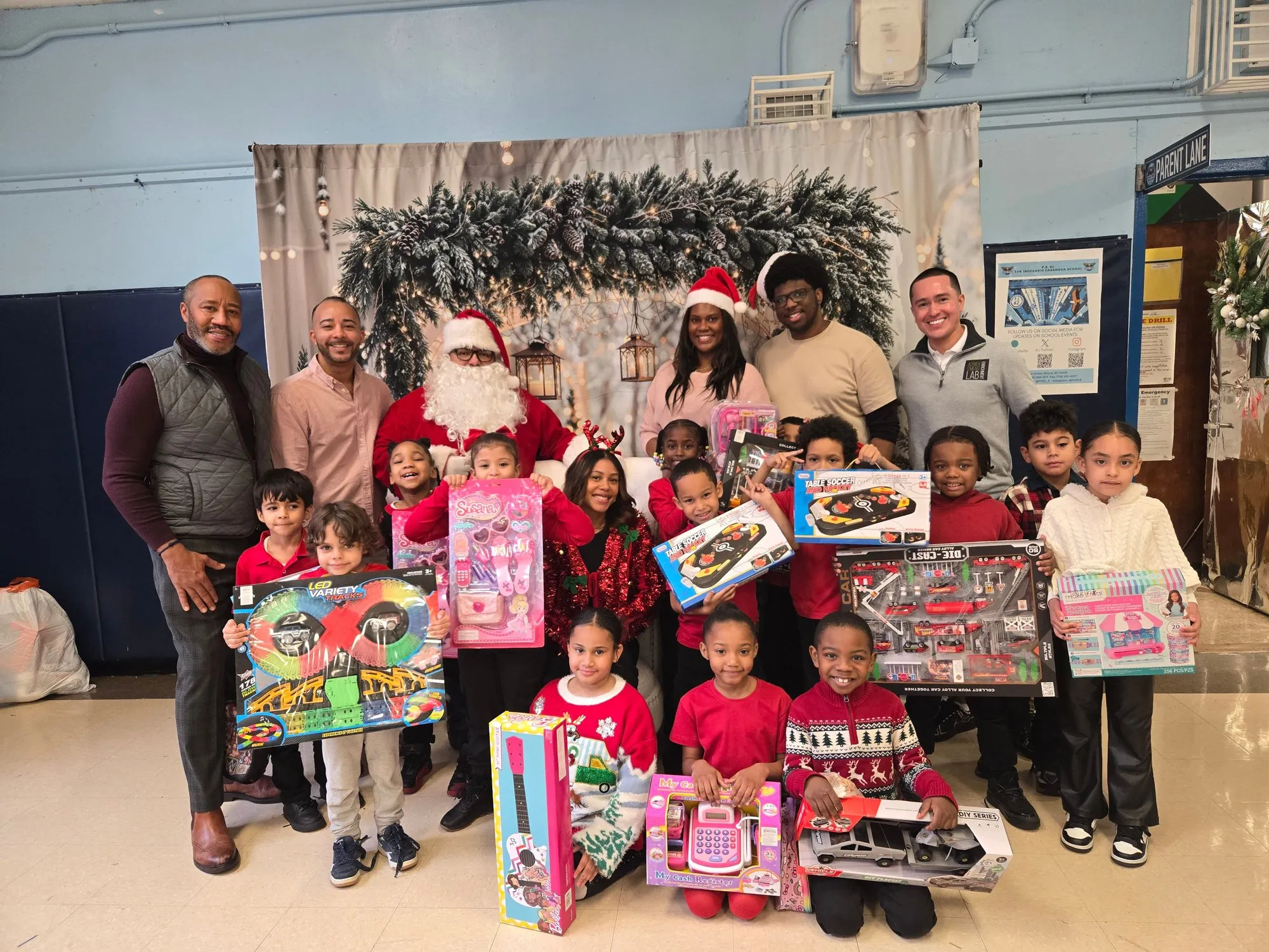 Natalia in a Santa hat with volunteers, Santa, and a group of children holding up toys at a holiday toy drive
